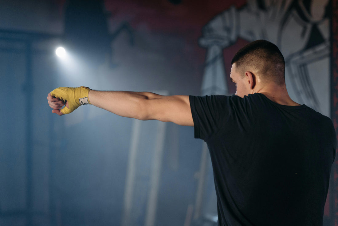 Boxer with yellow hand wraps extending a punch, demonstrating correct fit before choosing boxing glove size