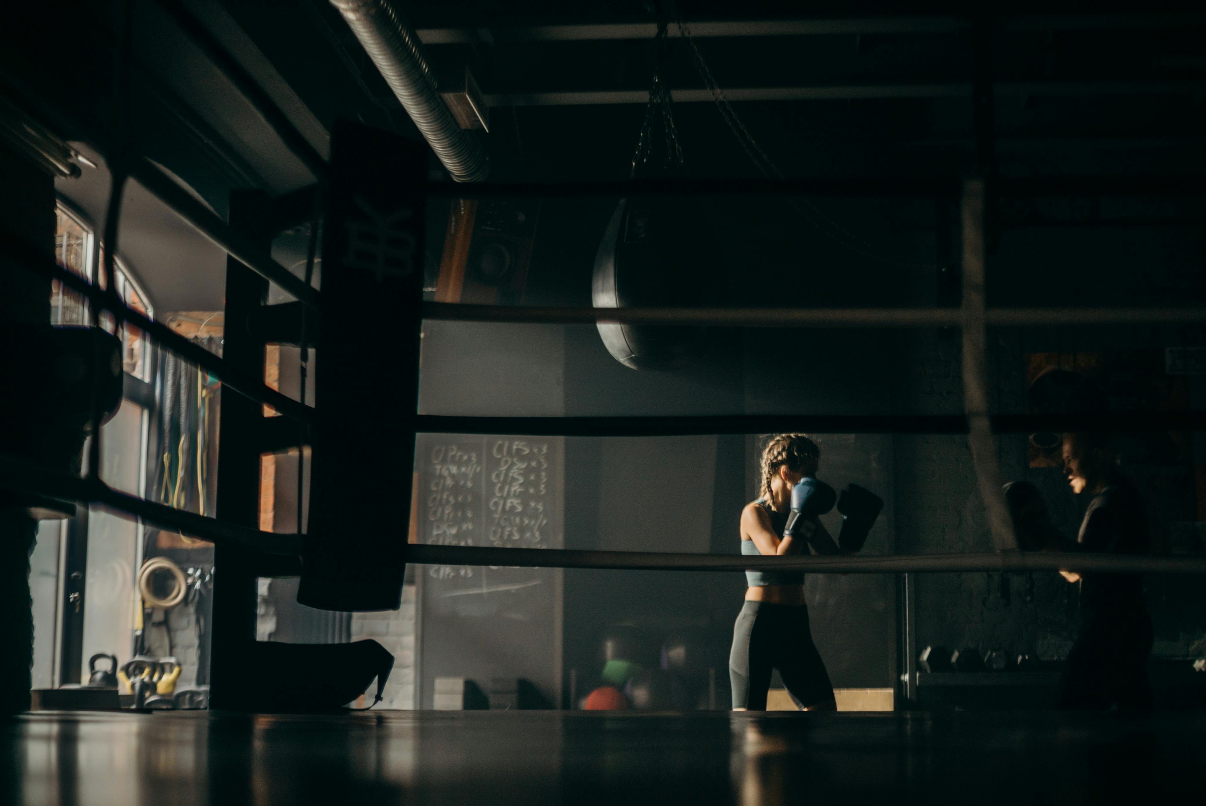 Boxer training inside a dimly lit gym with boxing workout equipment, representing the Fereli Code mindset of discipline and focus.