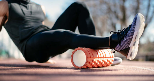 A person foam rolling their legs outdoors as part of an active recovery routine on a boxing rest day.