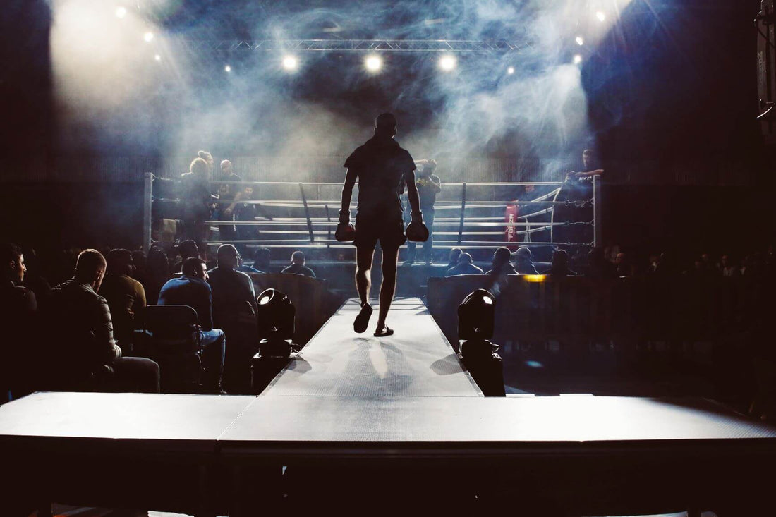 A boxer walks toward the ring under bright lights and smoke, symbolizing focus, confidence, and mental toughness before a fight.