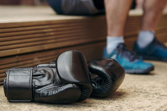 worn boxing gloves on the floor after training showing signs of boxing equipment lifespan