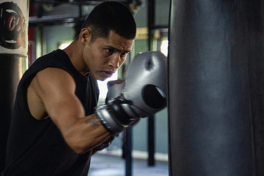 Boxer wearing boxing gloves practicing bag work on a heavy bag during training