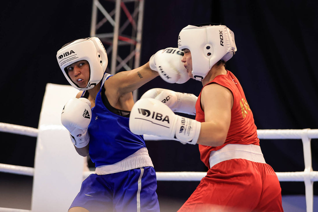 Two amateur boxers wearing protective headgear exchange punches in the ring, demonstrating timing, distance control, and high boxing IQ during a competitive bout.