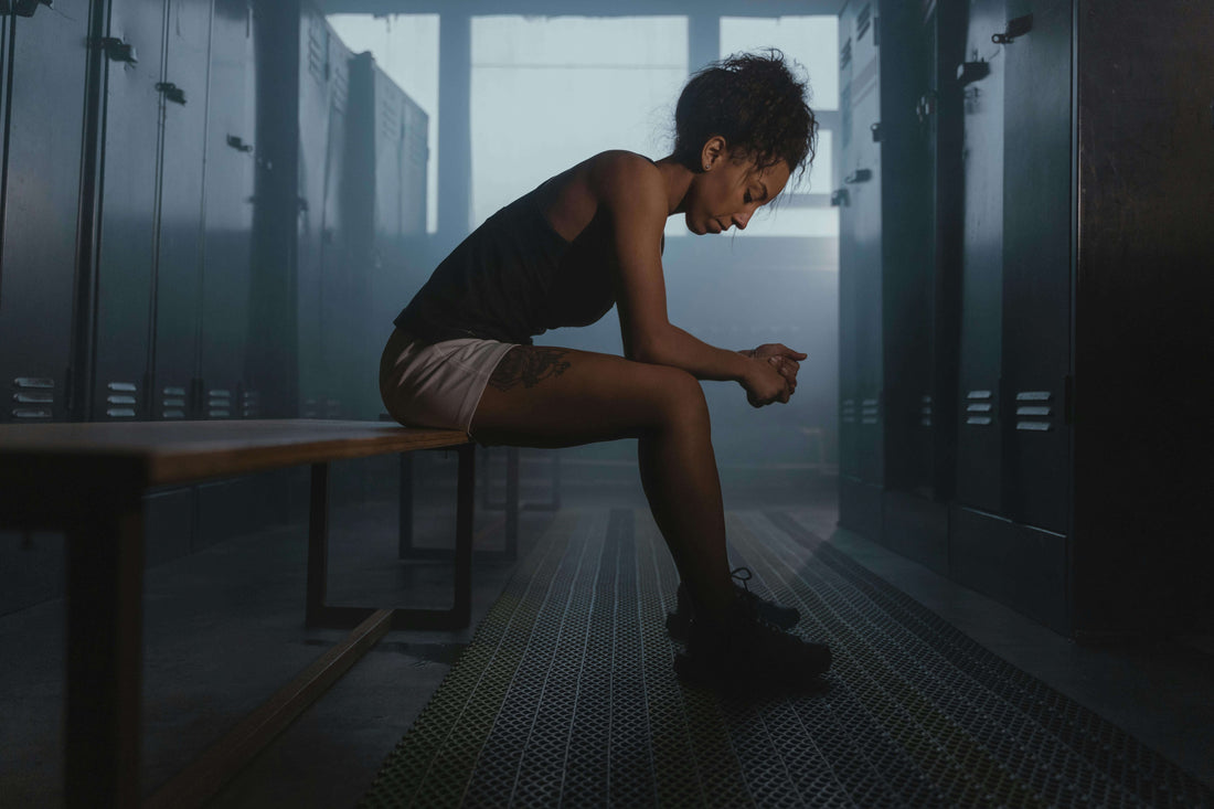 Boxer sitting in a locker room focusing before training, illustrating boxing mental training, focus, and mindset development.