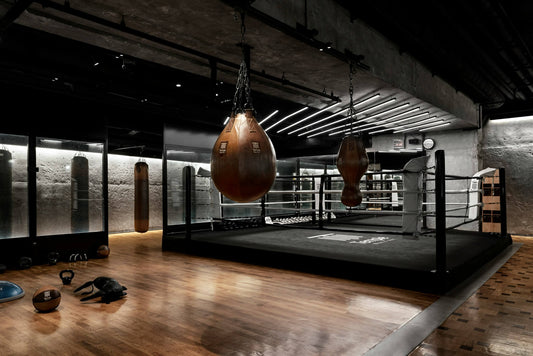 Empty boxing gym with heavy bags and a ring, symbolizing discipline, consistency, and boxing motivation during solo training sessions.