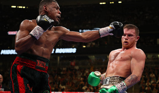 A boxer, Canelo Alvarez, slipping a punch and landing a sharp counter right hand during a professional match, demonstrating fast reaction time and precise timing.
