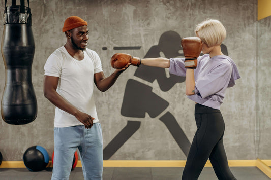 Boxer breaking in new boxing gloves during a pad training session with a coach in the gym