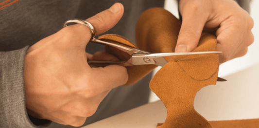 Craftsman cutting leather pieces as part of the boxing glove manufacturing process