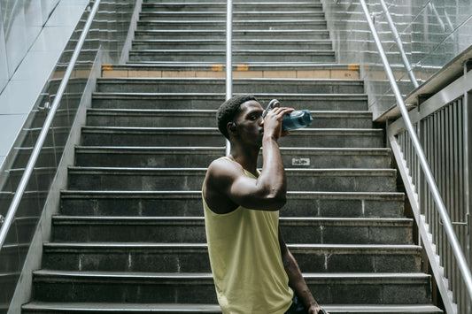 A man in athletic gear drinking water after training, representing the daily habits, discipline, and recovery practices of elite fighters in fighting, boxing training, and boxing exercises.