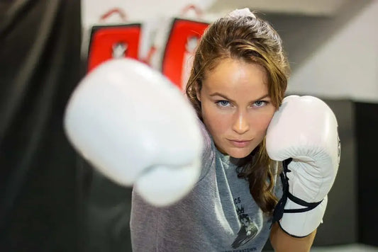 Female beginner boxer training with white gloves, highlighting common boxing glove mistakes beginners make during early training sessions.
