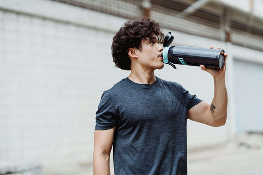 A male athlete drinking water from a large bottle during training, highlighting the importance of hydration for fighters.