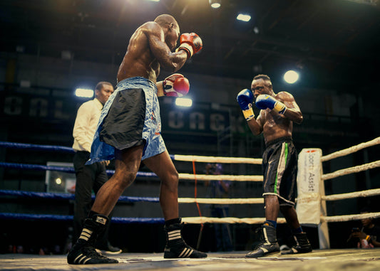 Two boxers facing off in the ring wearing premium boxing gloves, demonstrating quality craftsmanship and performance during a competitive bout