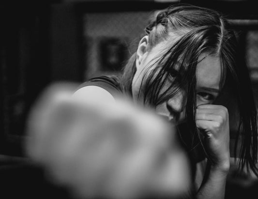 Close-up black and white photo of a woman throwing a boxing jab, capturing focus and precision during training.