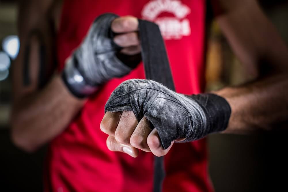 Boxer wrapping hands to improve wrist support and protection before training or sparring