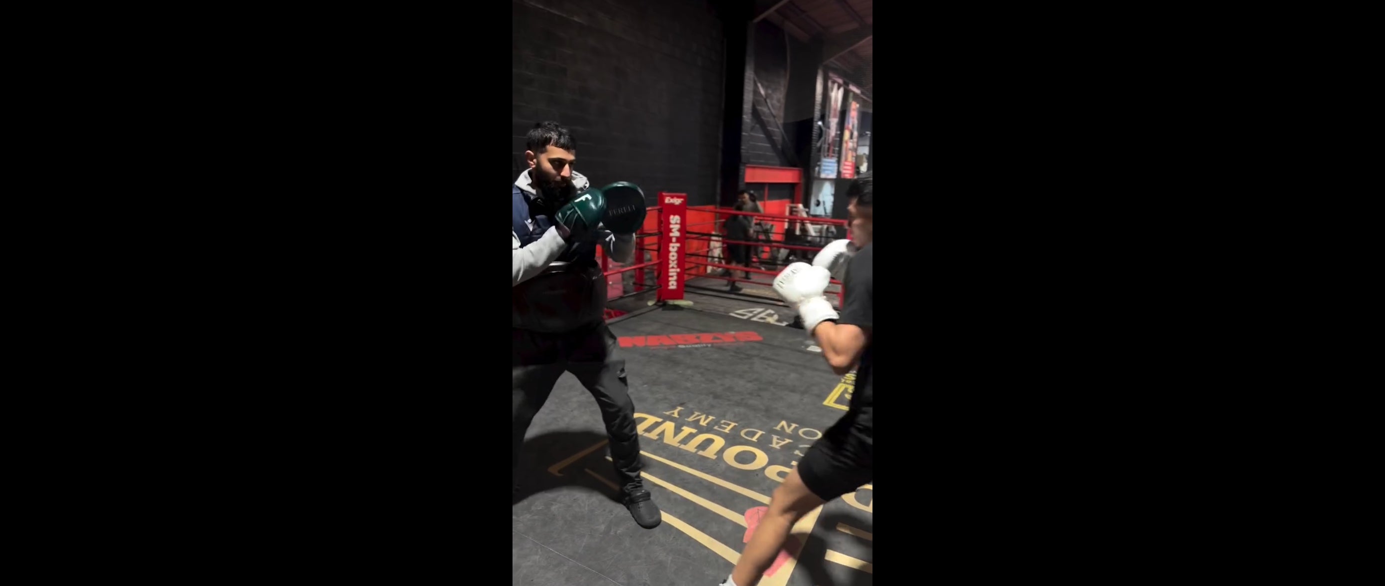 Load video: Coach Beano Ahmed training a young boxer using Fereli Focus Mitts inside a boxing ring, demonstrating live pad work in a real gym setting.