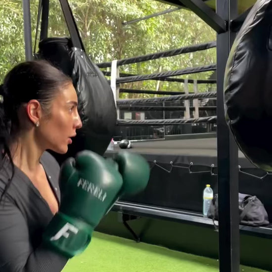 A female boxer using Fereli Evergreen boxing gloves for bag work