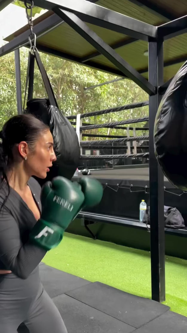 A female boxer using Fereli Evergreen boxing gloves for bag work